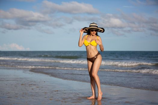 Beautiful young woman in sexy bikini on sand at sea beach.