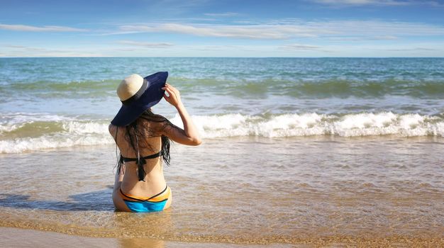 Beautiful young woman in sexy bikini on sand at sea beach.