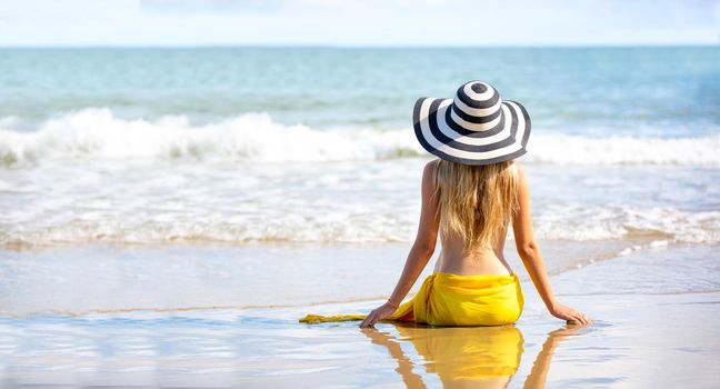 Beautiful young woman in sexy bikini on sand at sea beach.