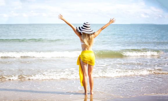 Beautiful young woman in sexy bikini on sand at sea beach.