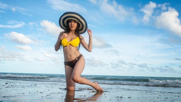 Beautiful young woman in sexy bikini on sand at sea beach.