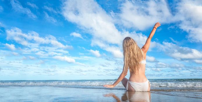 Beautiful young woman in sexy bikini on sand at sea beach.