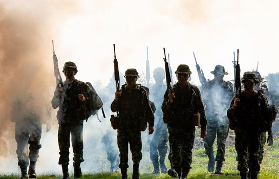 Silhouettes of soldiers during Military Mission at dusk
Silhouettes of army soldiers in the fog against a sunset, marines team in action, surrounded fire and smoke, shooting with assault rifle and machine gun, attacking enemy
