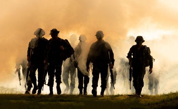 Silhouettes of soldiers during Military Mission at dusk
Silhouettes of army soldiers in the fog against a sunset, marines team in action, surrounded fire and smoke, shooting with assault rifle and machine gun, attacking enemy
