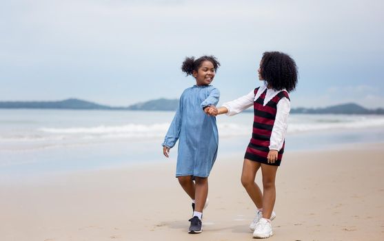 Kids playing running on sand at the beach, A group of children holding hands in a row on the beach in summer, rear view against sea and blue sky