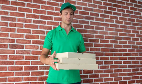 Young man delivering food to customer at doorway, Paper pocket and food containers in hands of a smiling deliveryman outdoors. Quality service of a restaurant.