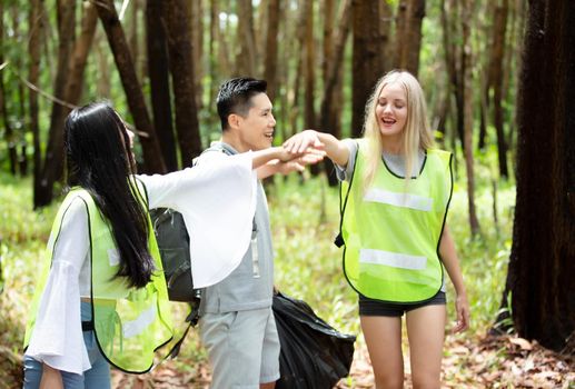 Green volunteering. Optimistic two volunteers holding garbage bag and help picking up trash at park, they're picking up the garbage and putting it in a black garbage bag. ecology protection concept.