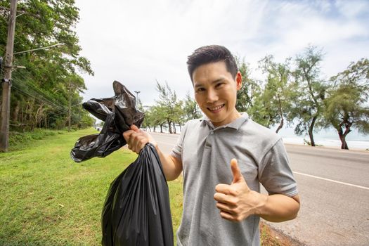 Green volunteering. Optimistic two volunteers holding garbage bag and help picking up trash at park, they're picking up the garbage and putting it in a black garbage bag. ecology protection concept.
