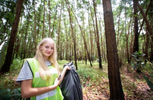 Green volunteering. Optimistic two volunteers holding garbage bag and help picking up trash at park, they're picking up the garbage and putting it in a black garbage bag. ecology protection concept.
