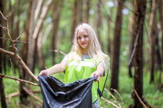 Green volunteering. Optimistic two volunteers holding garbage bag and help picking up trash at park, they're picking up the garbage and putting it in a black garbage bag. ecology protection concept.