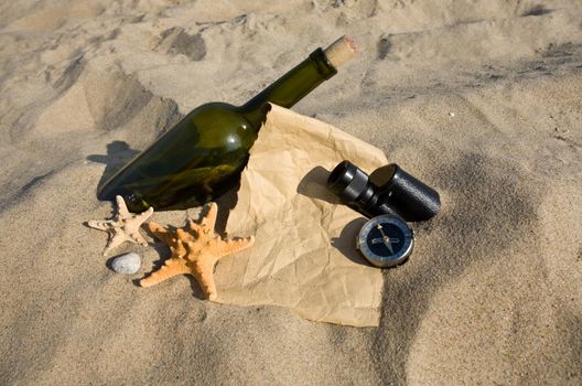 old paper, the compass, a sink and a bottle on sand background