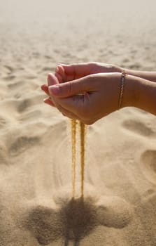 hand through the fingers of which pours sand