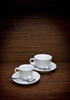 white cup with steaming coffee sitting on the oak table on grungy background