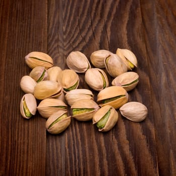 Roasted pistachios on natural wooden table background