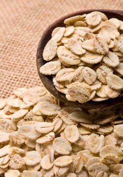 Oat flakes in spoon on wooden table