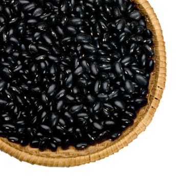Wicker plate with black grains beans close-up on white background
