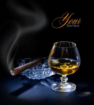 Glass of cognac with a cigar on dark sackground
