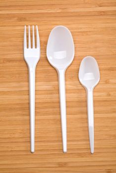 plastic disposable cutlery on a wooden background