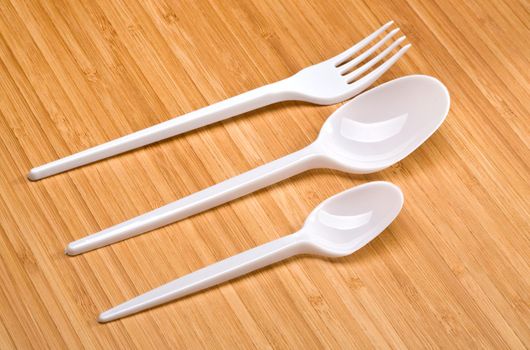 plastic disposable cutlery on a wooden background