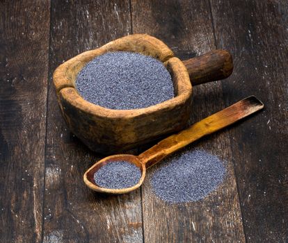 poppy seeds in a wooden bowl on a background of the old wooden table