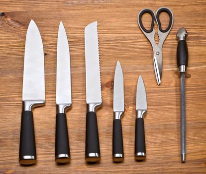 Collection of kitchen knives isolated on wooden background