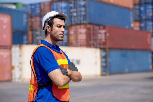 Portrait of engineer or foreman cargo container worker stand with arm-crossed in front of container tank stack with day light, factory and industrial worker support concept.