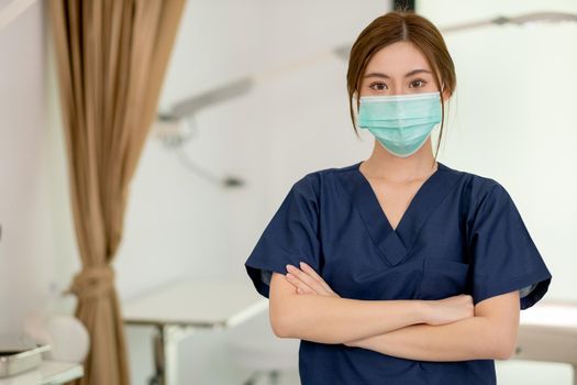 Beauty clinic worker wearing hygiene mask and stand with arm-crossed in workplace area. Beauty business for good appearance to people during covid-19 pandemic concept.