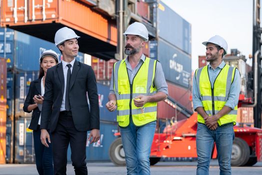 Group of cargo container workers or factory and engineer technicians walk and discuss together in workplace area. Concept of good teamwork support best success work of industrial business.