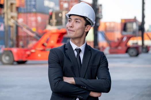 Portrait of engineer worker of factory technician with Chinese style stand in front of cargo container crane in workplace area. Concept of good support best successful for industrial business.