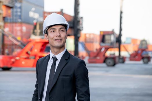 Portrait of engineer worker of factory technician with Chinese style stand in front of cargo container crane in workplace area. Concept of good support best successful for industrial business.