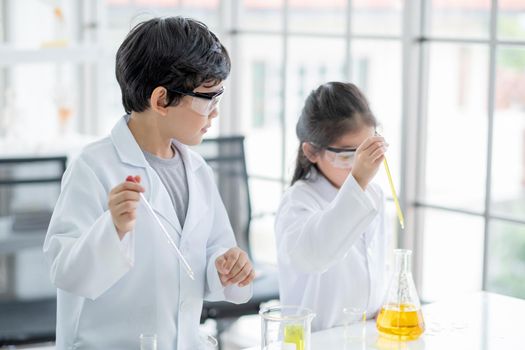 Little boy scientist enjoy to examine the color chemical in laboratory by using dropper and also interest little girl examine. Concept of good practice and education of science for children support.