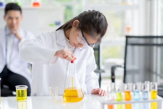 Lovely little girl scientist concentrate to test color chemical in laboratory by using dropper with day light. Concept of good practice and education of science for children support.