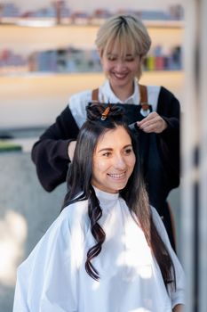 Beautiful Caucasian girl sit and smiling during beauty salon barber girl work with hair style in the shop. Beauty business for good appearance of people concept.