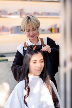 Beauty salon barber girl with smiling work with hair style of beautiful Caucasian girl sit in the shop.
