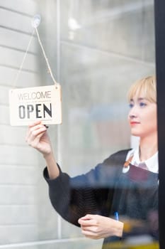 Banner of word, open, is held by beautiful Asian woman before start the work service for customer.