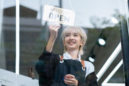 Lovely Asian beauty salon barber young girl hold banner of open the shop with smiling before work in the shop. Beauty business for good appearance for people concept.