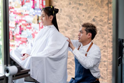 Asian beauty salon barber man sit and process of hair cut of long hair customer and he look concentrate for working. Concept of beauty business for good looking for people.