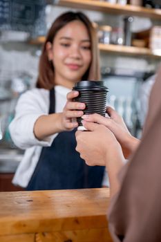 Close up hand of customer woman receive a cup of coffee from barista or coffee maker in coffee shop. Happy working with small business and sustainable concept.