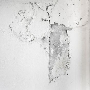 White cracked paint on wall. Peeling painted wall, texture, grunge background, cracked paint with white wall with window.