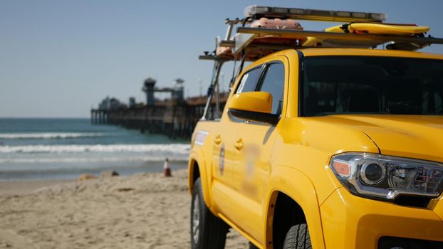 Yellow lifeguard car, Oceanside beach, California USA. Coastline rescue life guard pick up truck, lifesavers vehicle. Iconic auto and ocean coast. Los Angeles vibes, summertime aesthetic atmosphere.