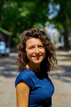 Beautiful curly brunette girl model walks on a summer day.