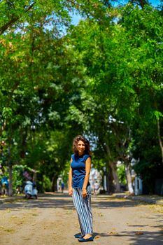 Beautiful curly brunette girl model walks on a summer day.