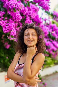 Beautiful young girl model brunette posing with blooming purple flowers in Turkey on the island of Buyukada.