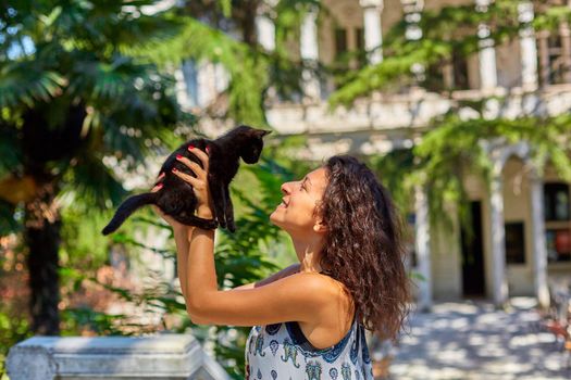 A young girl plays with a black kitten she found on the street.