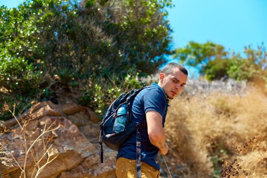 Weekend trekking. A guy with a backpack walks on the rocks. Active rest and enjoyment of nature.