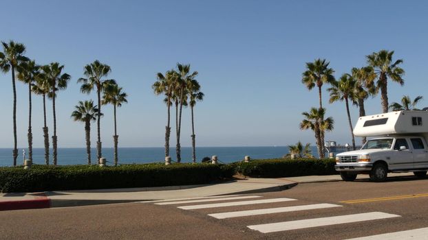 Motorhome trailer or caravan for road trip. Waterfront tropical palm trees and pacific ocean beach, Oceanside California USA. Beachfront vacations in camper van, RV motor home. Mobile home campervan.