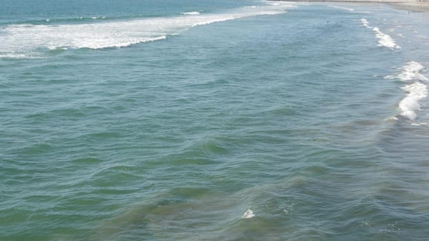 Pacific ocean big waves splashing, California coast USA. Water surface texture and sea foam. Seascape near beach, tide of blue water. Frome above, top down high angle view. Sunny tropical summer day.