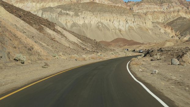 Road trip to Death Valley, Artists Palette drive, California USA. Hitchhiking auto traveling in America. Highway, colorful bare mountains and arid climate wilderness. View from car. Journey to Nevada.