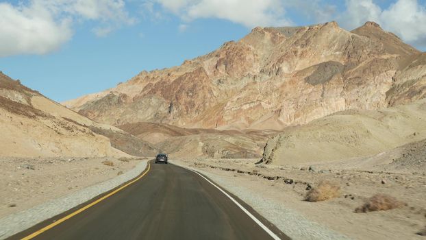 Road trip to Death Valley, Artists Palette drive, California USA. Hitchhiking auto traveling in America. Highway, colorful bare mountains and arid climate wilderness. View from car. Journey to Nevada.