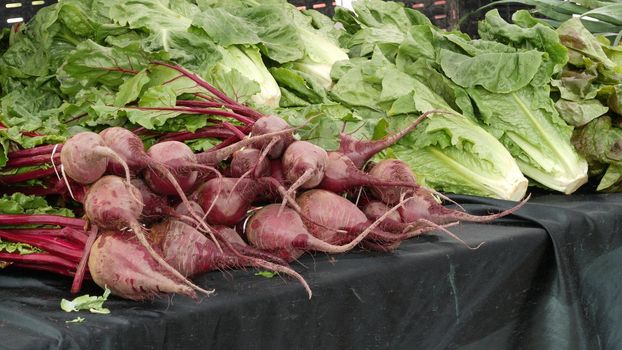 Organic vegetables on counter, fresh local produce homegrown raw veggies on marketplace stall. Healthy vegetarian food, Farmers market in Oceanside California USA. Agricultural farm harvest selling.